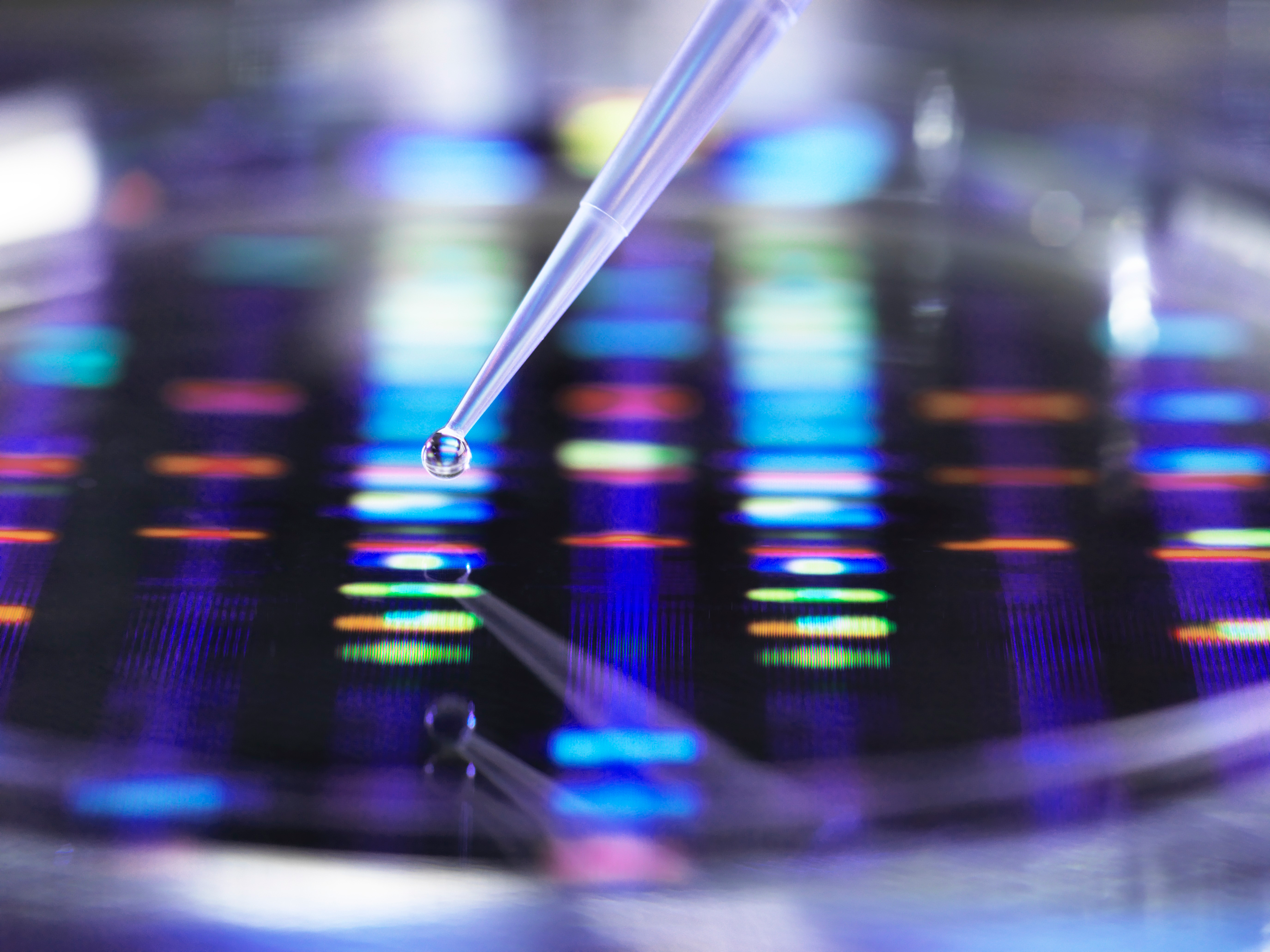 A close-up of a pipette dropping a solution in a laboratory setting